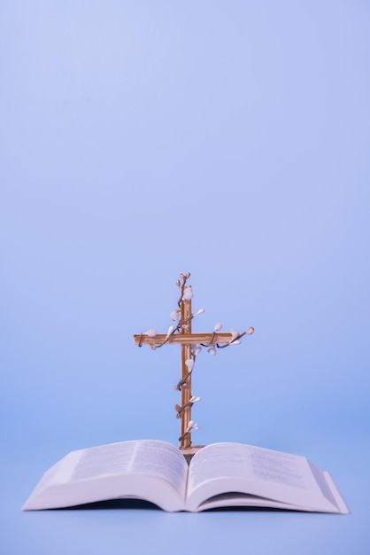 Flores decoradas cruzadas con la Santa Biblia sobre fondo púrpura Concepto minimalista de vacaciones de Pascua