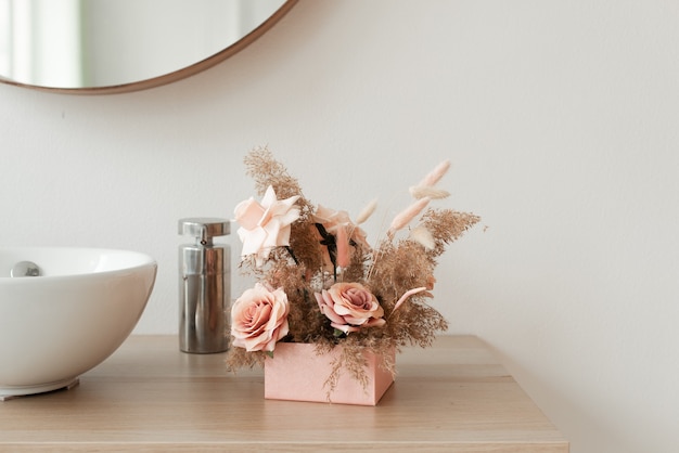 Flores decorativas minimalistas en una caja rosa sobre un fondo de espejo