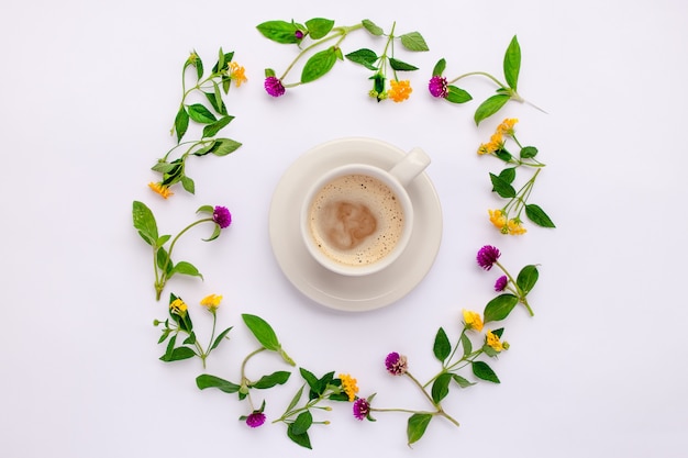Flores do Prado e flores silvestres dispostas em círculo com a xícara de café. Postura plana.