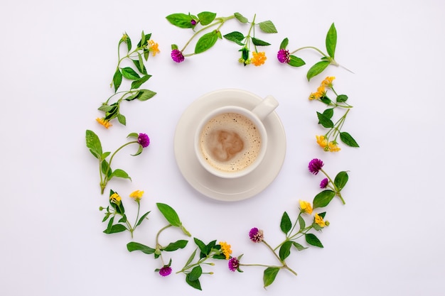 Flores do prado e flores silvestres dispostas em círculo com a xícara de café. postura plana.