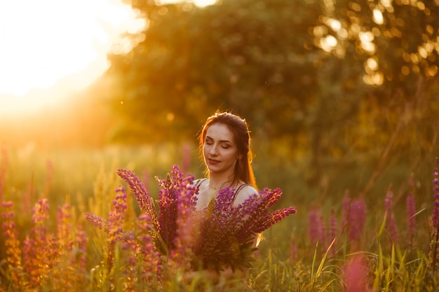 Flores e a palma da mulher no campo. Sol da tarde iluminada