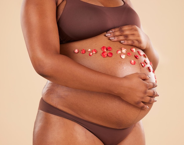 Flores e estômago da mulher grávida no fundo do estúdio do corpo maternidade e cuidados de saúde Closeup abdômen plantas florais e brilho da gravidez da mãe barriga cuidados com a pele e ginecologia do parto natural