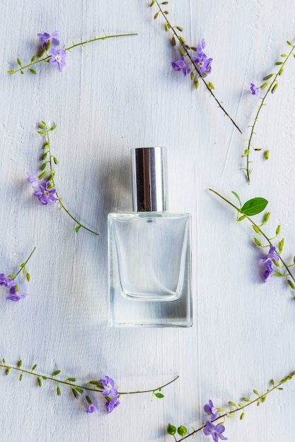 Flores e frasco de perfume em uma mesa de madeira branca