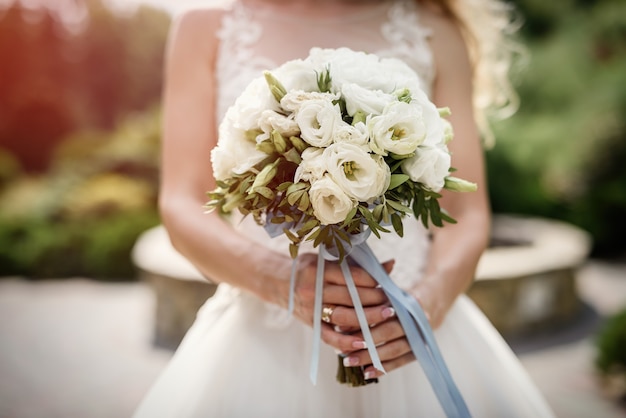 Flores em buquê. Noiva segurando flores brancas em buquê de casamento