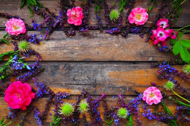 Flores em um círculo em um cartão postal de fundo de madeira para as rosas de férias gerânios lavanda sage um