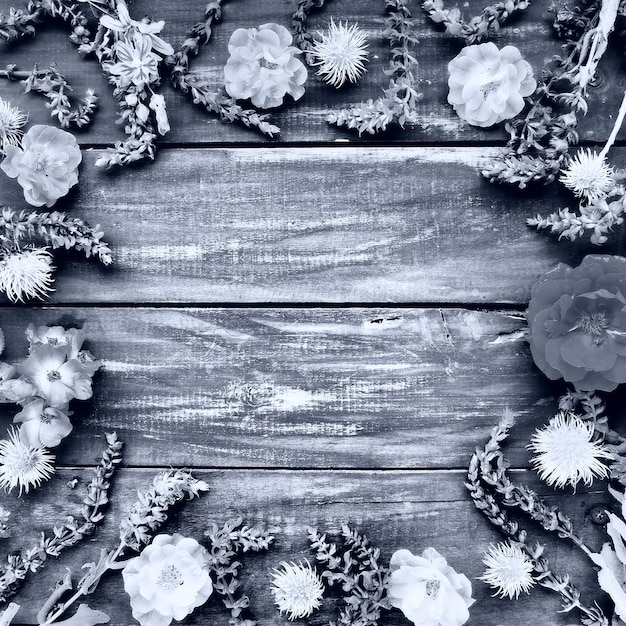 Flores em um círculo em um fundo de madeira Rosas de cartão postal gerânios lavanda sálvia e castanhas peludas são colocadas ao longo das bordas Espaço da cópia de fundo plano lay Foto monocromática branca preta