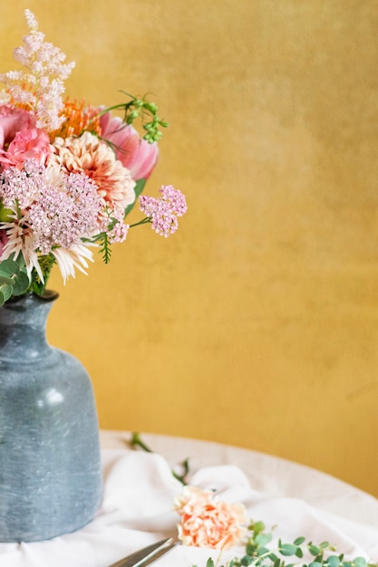 Flores em um vaso perto de uma parede amarela