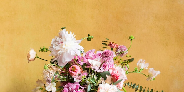 Flores em um vaso por uma parede amarela