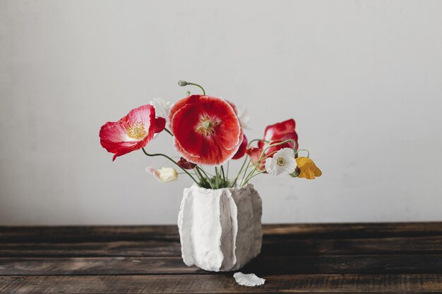 Flores em vaso moderno, naturezas mortas rústicas, belas papoulas vermelhas e amarelas em bancos de madeira envelhecidos, flores silvestres de verão, papel de parede floral, espaço para texto.