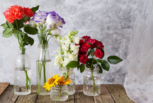 Flores em vasos de garrafa em uma mesa de madeira