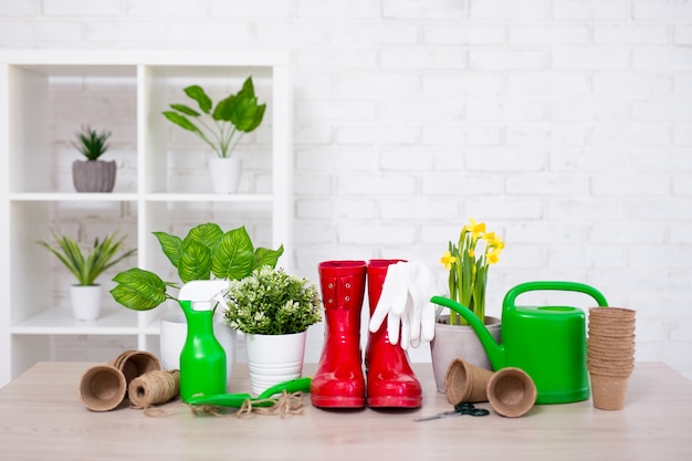 Flores em vasos e ferramentas de jardinagem com espaço para texto sobre parede de tijolo branco