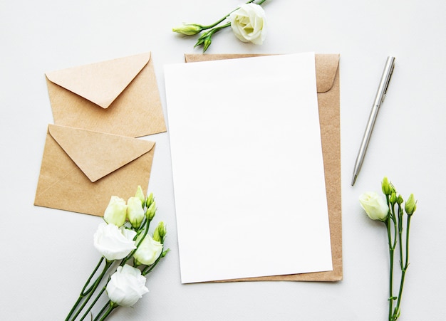 Flores eustoma brancas, envelopes e folha de papel branco em branco