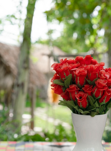 Flores falsas de rosas vermelhas em vaso na mesa