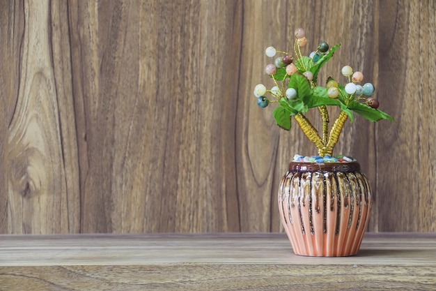 Flores falsas en un jarrón colocado sobre una mesa de madera con espacio para copiar madera de diseño