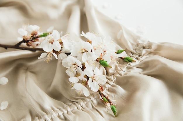 Flores de flor blanca en ropa de tela de seda beige sobre fondo blanco.