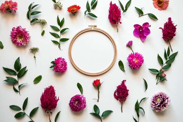 Foto flores frescas em close-up e folhas verdes espalhadas sobre um fundo branco espaço de cópia de círculo no centro