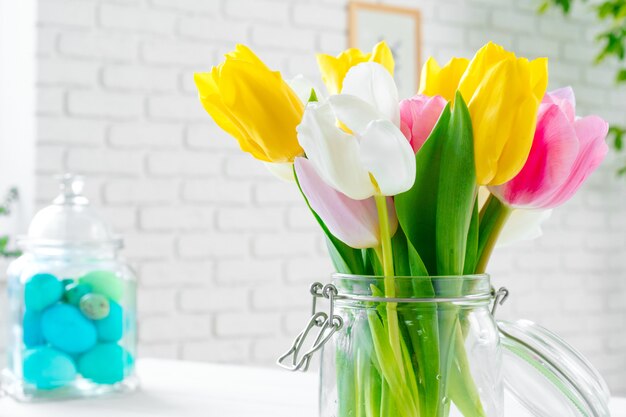 Flores frescas de primavera con huevos pintados para la celebración de Pascua