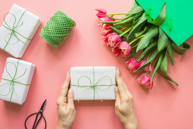 Flores frescas de tulipán rojo en bolsa de papel verde en rosa. primavera. día de la madre.