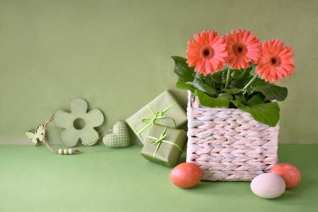 Flores de gerbera de coral, huevos de Pascua y decoraciones de primavera en papel verde, espacio de copia