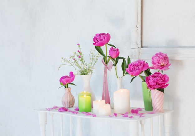 Flores en jarrones y velas sobre fondo blanco.