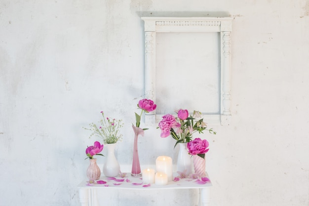 Flores en jarrones y velas sobre fondo blanco.