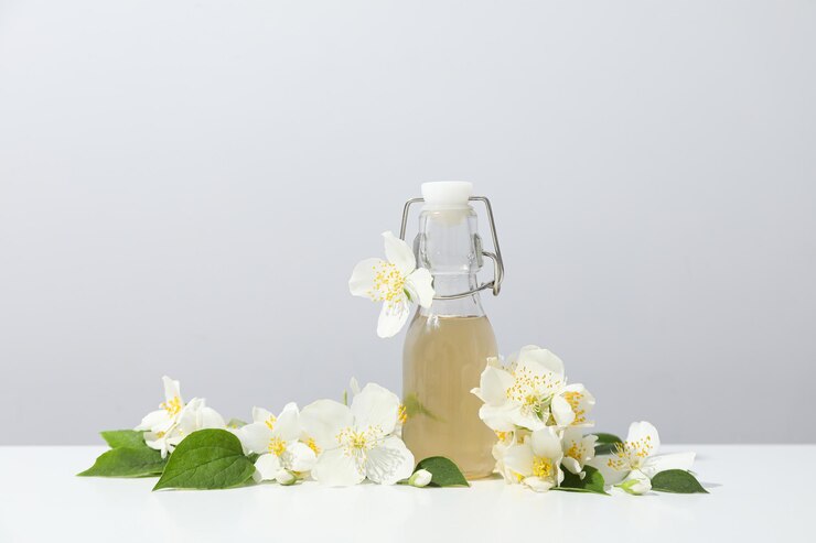 Flores de jazmín y botella de vidrio sobre fondo claro