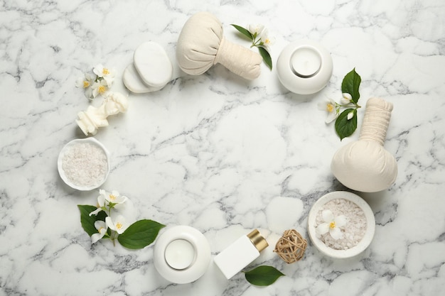 Flores de jazmín y un conjunto de elementos esenciales de spa en una mesa de mármol blanco plana Espacio para texto