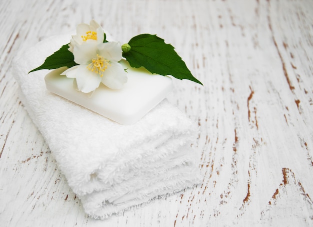 Flores de jazmín y jabón en mesa de madera.