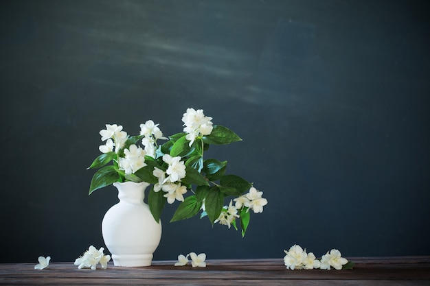 Flores de jazmín en jarrón de cerámica sobre fondo blanco.