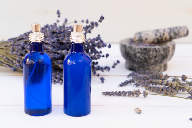 Flores de lavanda y aceite de lavanda en dos botellas azules