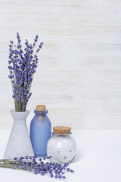 Flores de lavanda y botellas de vidrio, fragante sal marina. Concepto de spa con espacio de copia.