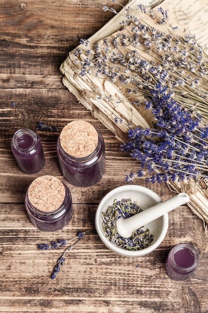 Flores de lavanda secas en un mortero con una botella de aceite esencial de lavanda