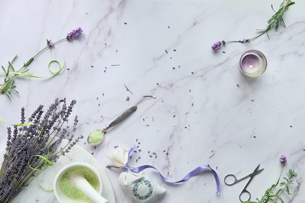 Flores de lavanda, tanto frescas como secas. Plano sobre mármol claro. Bolsitas de lavanda artesanales y sales de baño caseras.