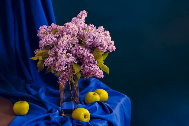 Flores lilas en un jarrón sobre una mesa sobre un fondo azul.