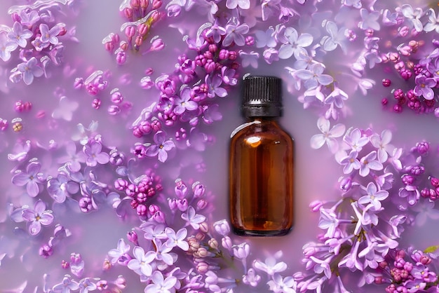 Flores lilas en leche con una botella transparente para cosméticos foto desde arriba diseño con flores