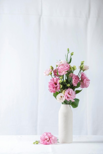 Flores de lisianthus rosa en jarrón blanco