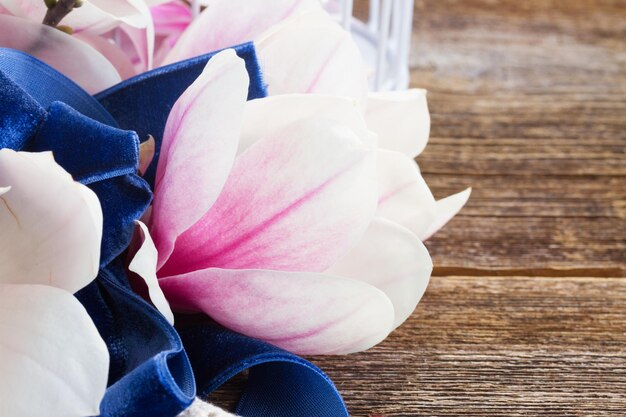 Flores de magnolia con perlas sobre mesa de madera