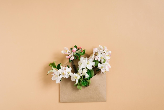 Flores de manzana blanca en un sobre de papel artesanal sobre un fondo beige El concepto de las vacaciones de primavera