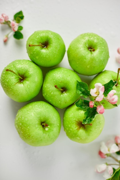 Flores de manzana planas y manzanas verdes maduras sobre un fondo blanco