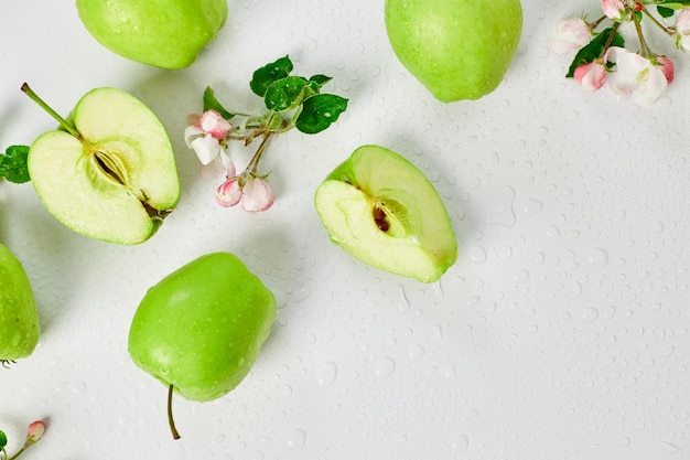 Flores de manzana planas y manzanas verdes maduras sobre un fondo blanco