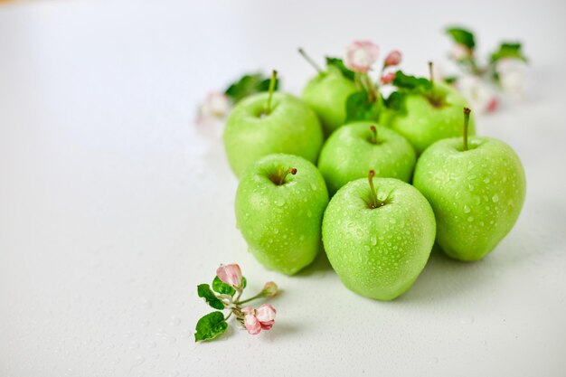 Flores de manzana planas y manzanas verdes maduras sobre un fondo blanco