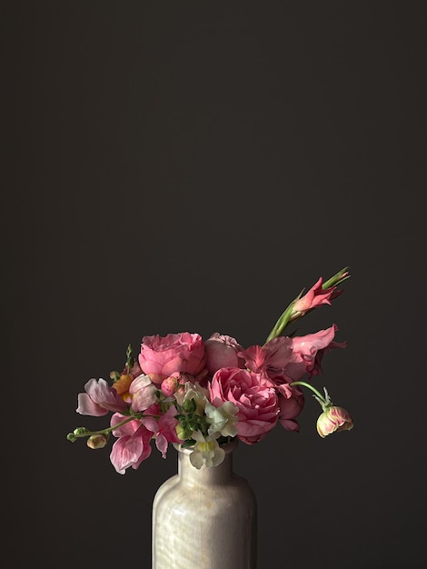 Flores Natureza morta Lindas flores cor-de-rosa em vaso à luz sobre fundo cinza mal-humorado Composição artística elegante de rosas snapdragon ranunculusgladiolus Papel de parede vertical floral