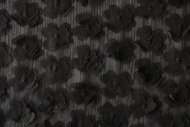 Flores negras adheridas a tela gris diseñadas para la fabricación de ropa y patrones creativos.