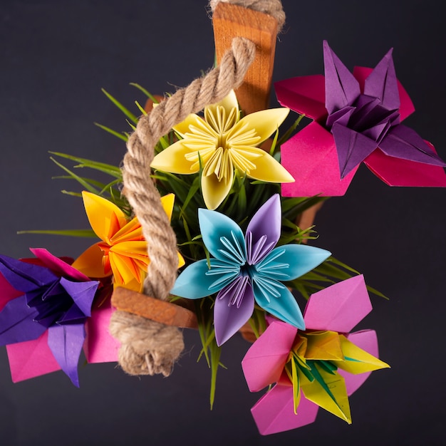 Foto flores de papel de colores hechos a mano origami bouquet paper craft art en una canasta con hierba en el estudio en blackbackground