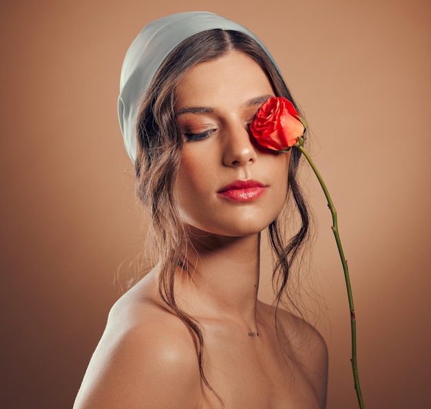 Flores pensando y mujer con maquillaje belleza floral bienestar y creatividad sobre un fondo de estudio marrón Flor de paz y modelo con una rosa para creatividad estética de lujo e idea para cosméticos