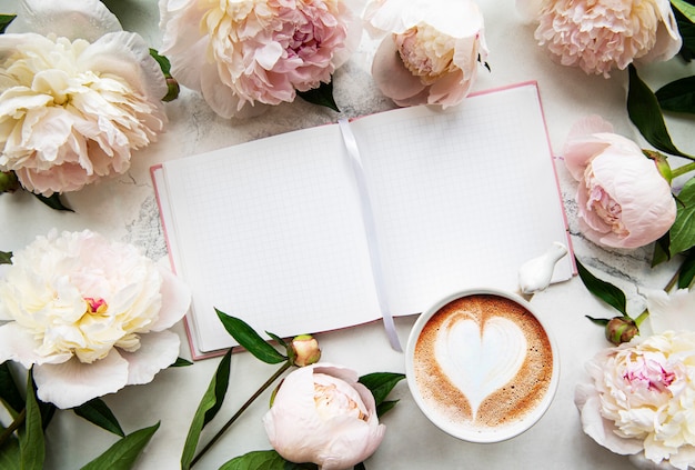 Flores de peonía, cuaderno y café