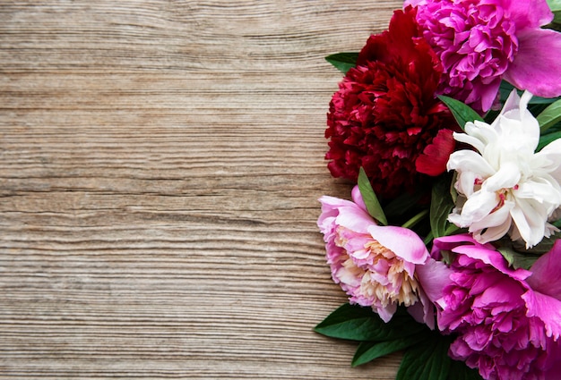 Flores de peonía rosa como un borde en una superficie de madera vieja