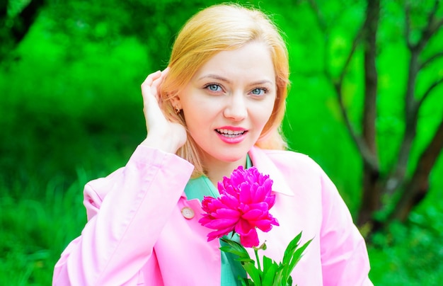 Flores de peonía, tiempo de primavera, hermosa niña con flor, mujer romántica con flor rosa en el parque.