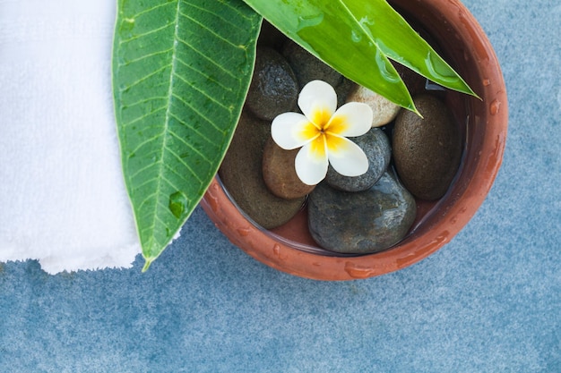 Flores y piedras para un tratamiento de masaje relajante sobre fondo azul.