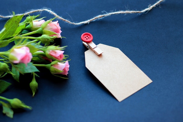 Foto flores, pinzas decorativas y papel para notas sobre un fondo oscuro. concepto de felicitaciones por las vacaciones.